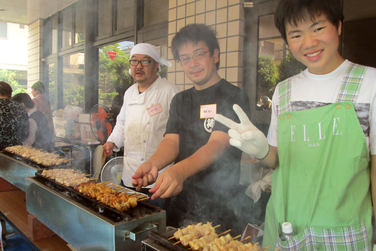 焼き鳥を焼く若者と青年