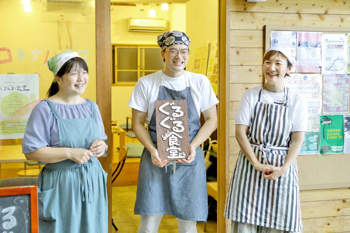 ぐるぐる食堂を運営する3人。真ん中の西加さんが看板を持っている。