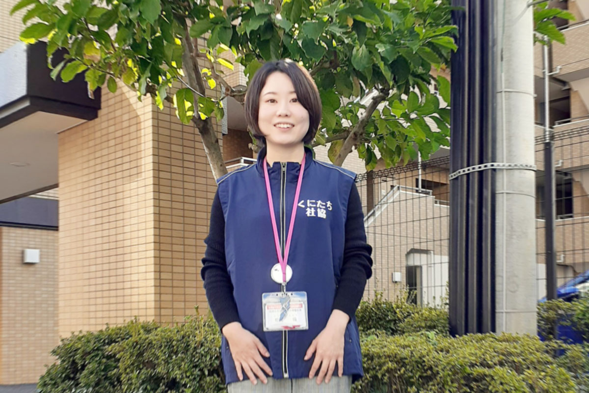 木を背景に女性の職員が写っている