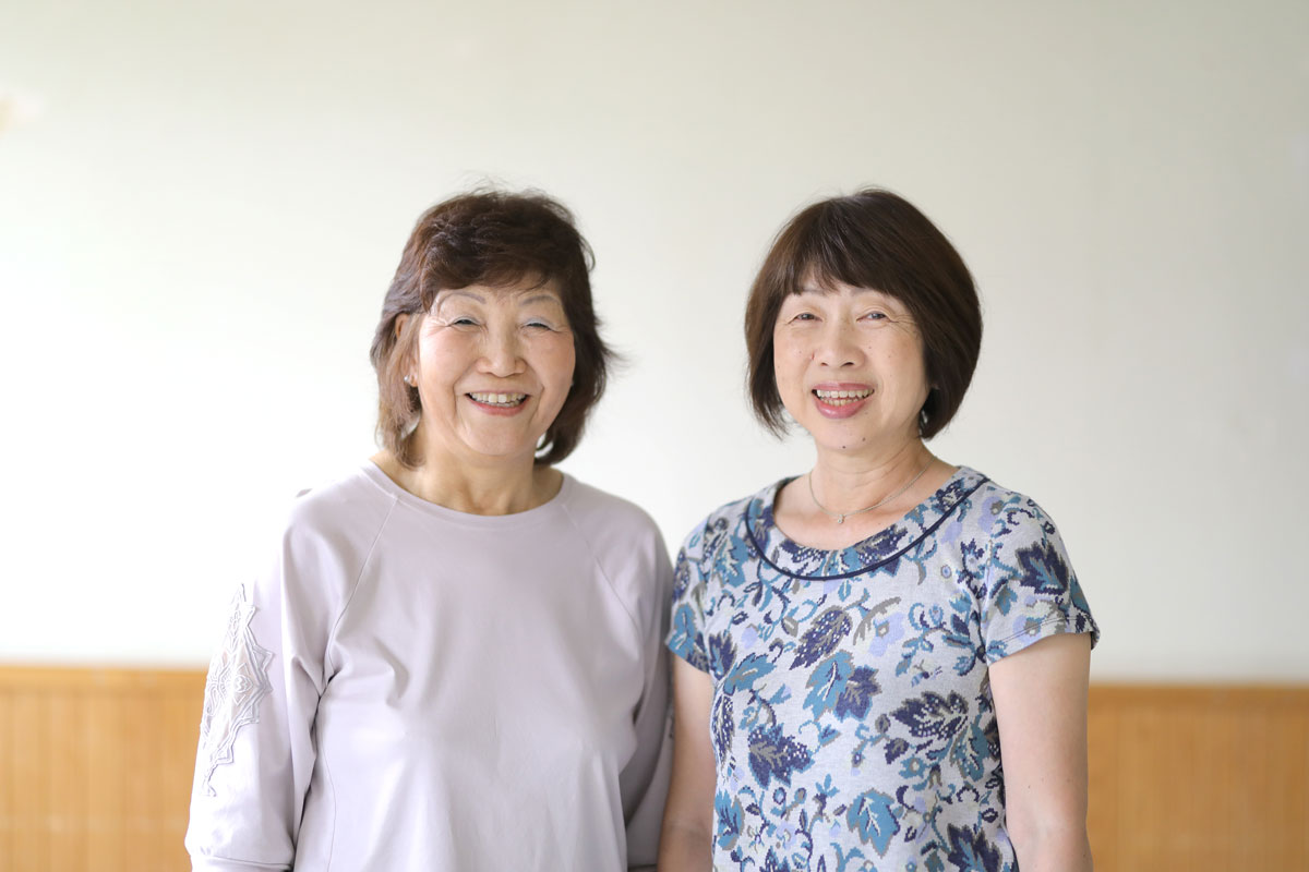 白い壁を背に中年の二人の女性が笑顔で写っている。