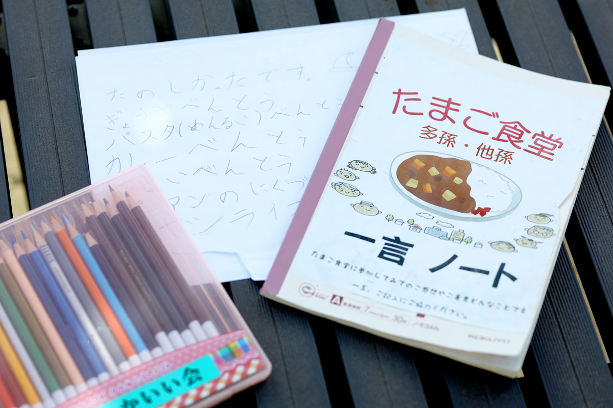 たまご食堂、一言ノートと書かれたノートが写っている。こどもの感想メッセージが書かれた画用紙と一緒に置かれている。