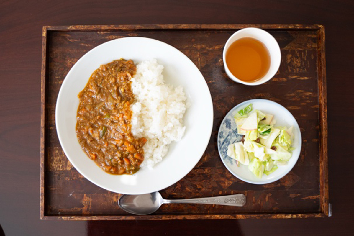 おぼんにのせられたキーマカレーとサラダ、お茶。