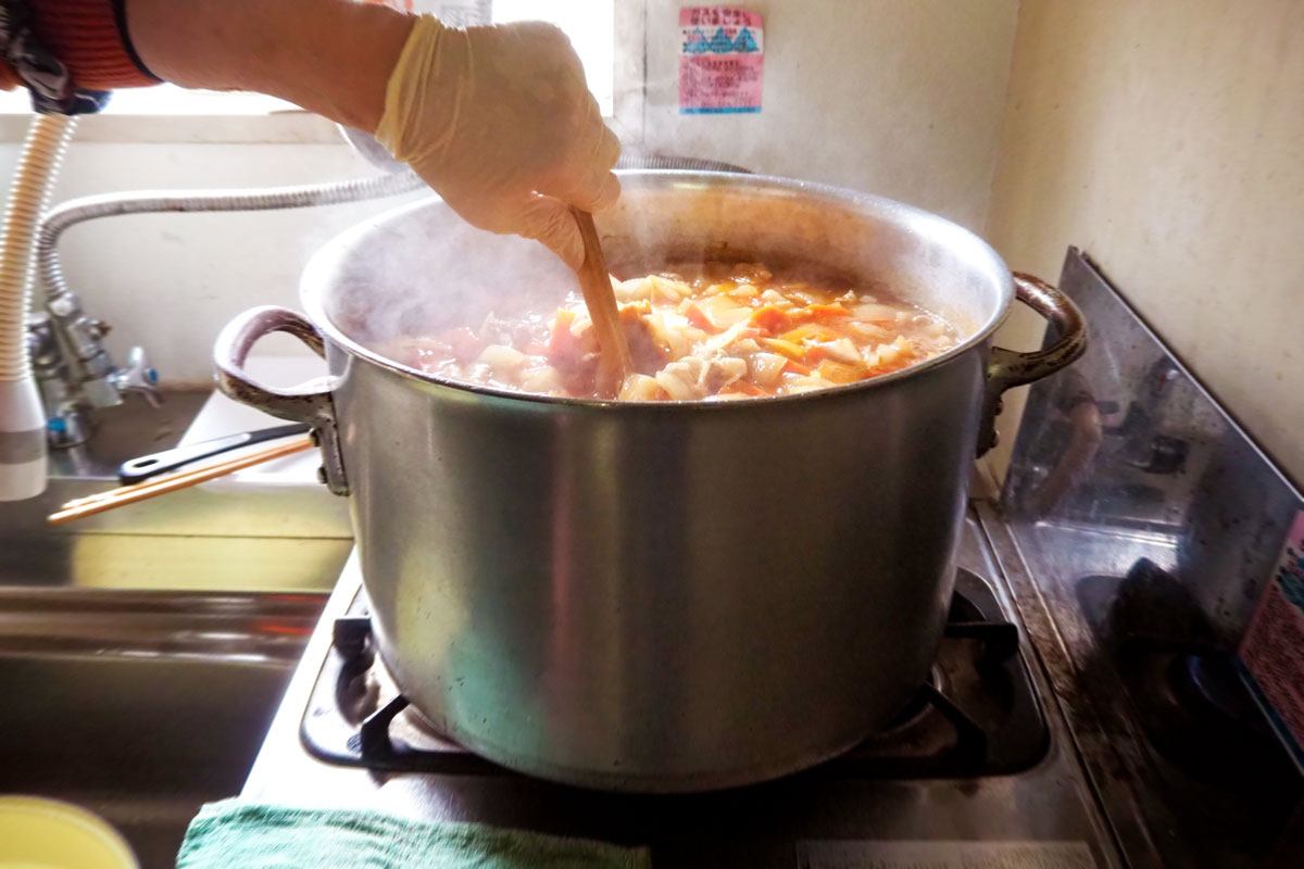 台所の窓から日が差している。大きな寸胴鍋でぐつぐつとカレーが煮込まれていて、立ちのぼる湯気が光っている。手袋をはめた手でへらを使い焦げないよう混ぜている。