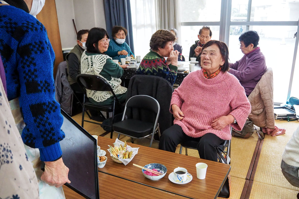 スタッフがコーヒーとお茶菓子を配膳しながら参加者と話をしている。